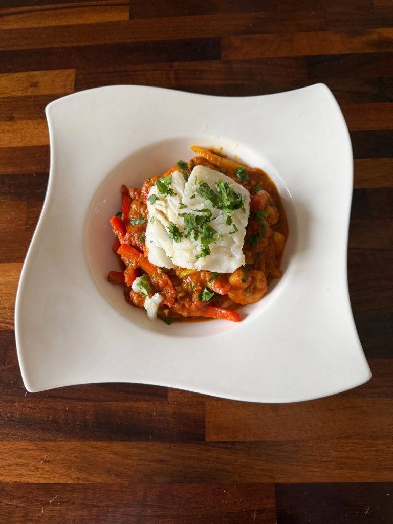 Pan-fried cod on a red pepper, tomato and prawn jalfrezi, garnished with fresh coriander