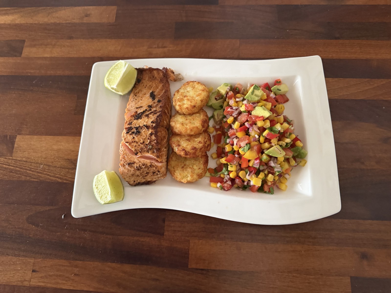 Spiced salmon fillet with sweetcorn, avocado and pepper salsa and lime wedges
